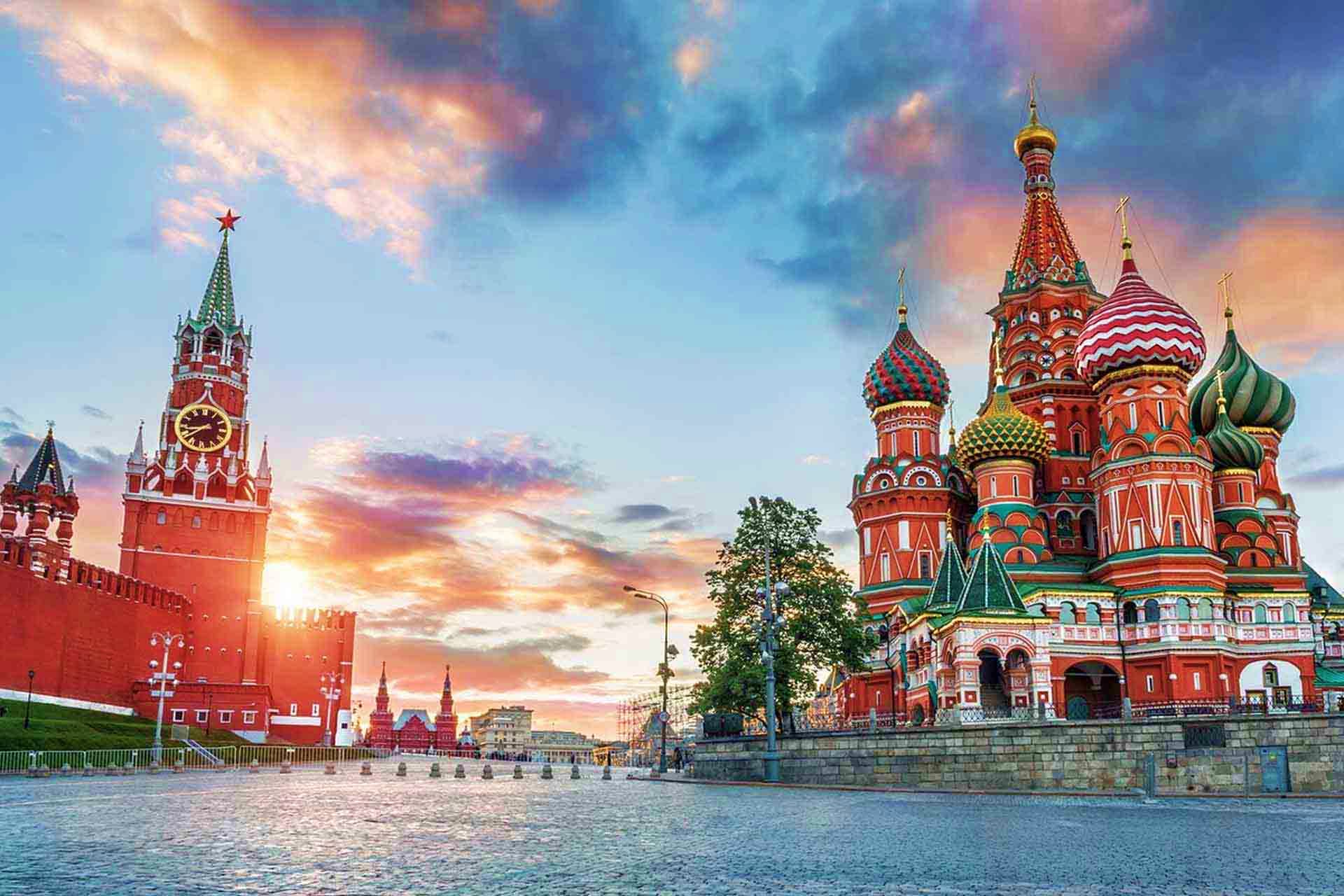 Russia Visa Red Square in Moscow at sunset featuring the Kremlin tower on left and Saint Basil's Cathedral with colorful onion domes on r